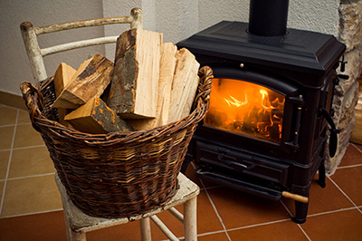 Burning woodstove next to wood in basket - Dunrite Chimney