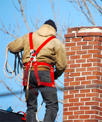 Chimney technician wearing safety harness next to chimney waterproofing crown - Dunrite Chimney