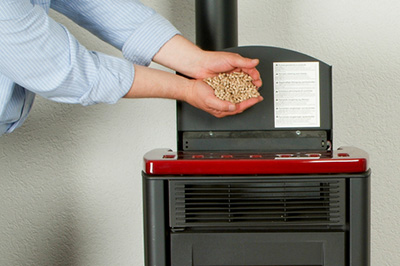 Hands holding pellets over a pellet stove - Dunrite Chimney