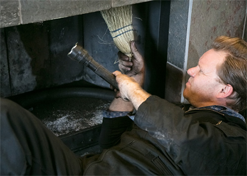 Original photo of man inspecting fireplace for rebuild - Dunrite Chimney Centereach NY Man inspecting fireplace for rebuild - Dunrite Chimney