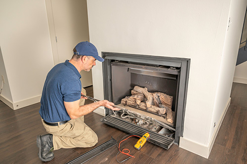 Original photo of man servicing fireplace insert - Dunrite Chimney Centereach NY Man servicing fireplace insert - Dunrite Chimney
