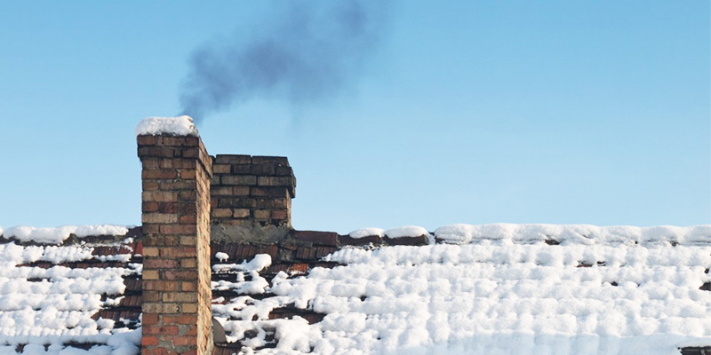 Smoking chimney on snowy roof - Dunrite Chimney stock photo