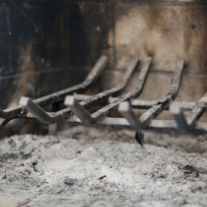 a fireplace grate in a firebox surrounding by ash