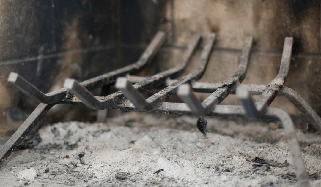 a fireplace grate in a firebox surrounding by ash