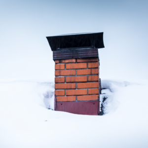 a brick chimney surrounded by a snowy roof