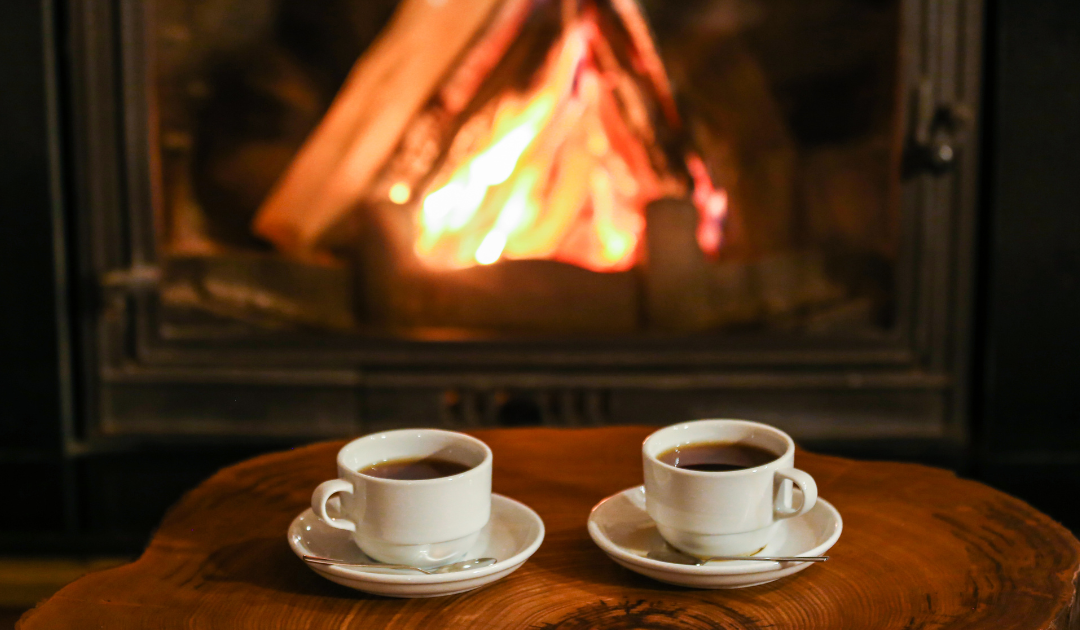 two white coffee cups by a wood-burning fireplace