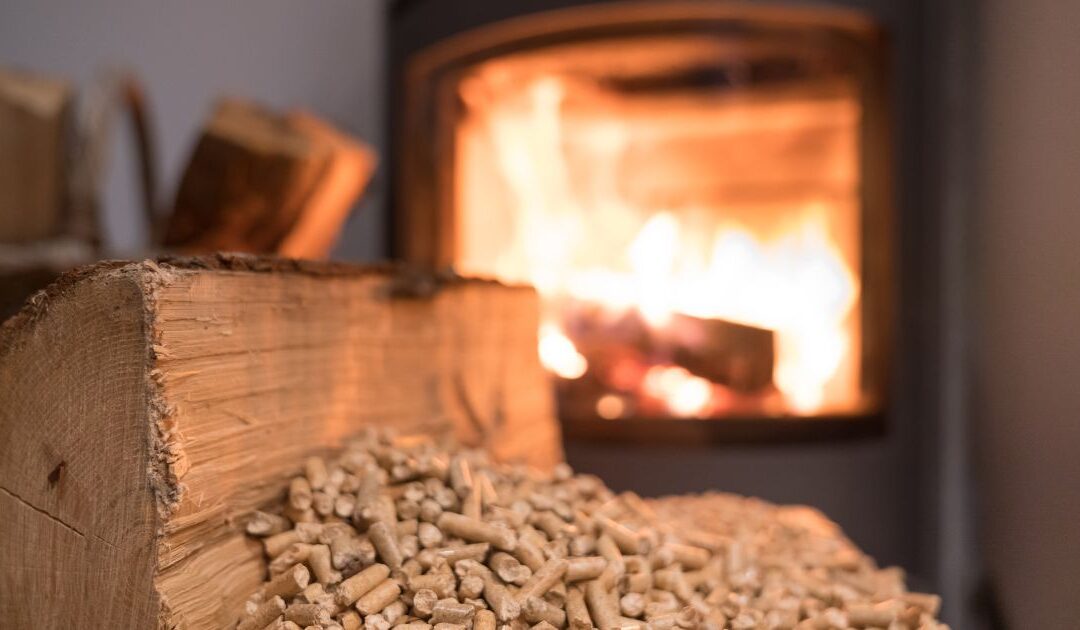 a close up view of a wood log on wood pellets with a wood stove in the background