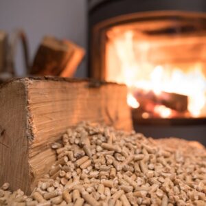 a close up view of a wood log on wood pellets with a wood stove in the background