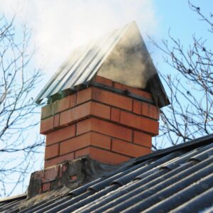 a brick chimney with a pointed cap with smoke billowing out