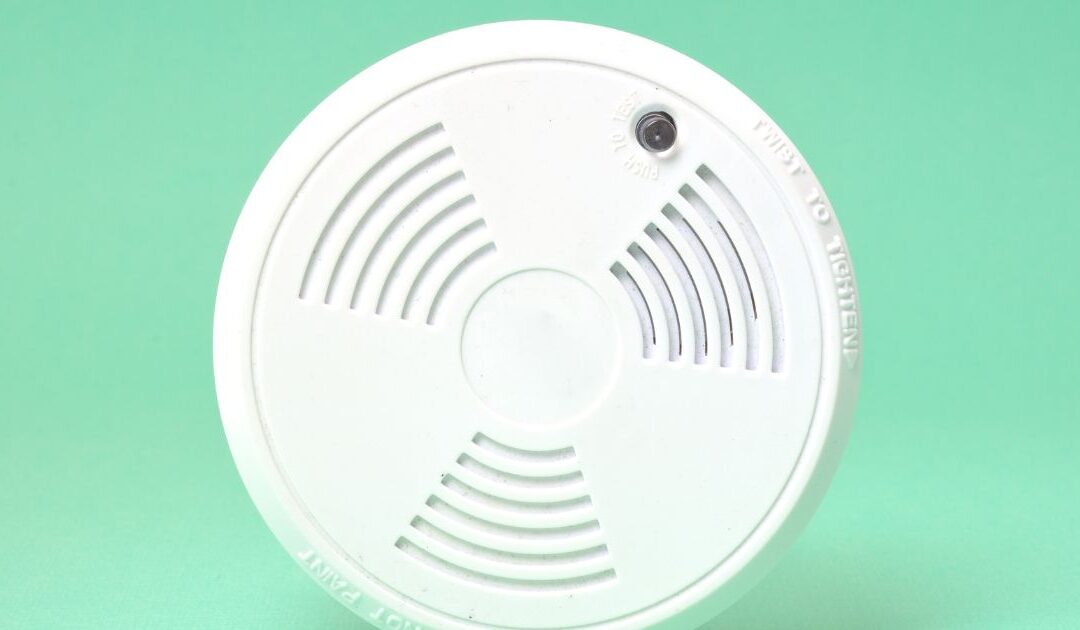 a round white smoke detector with a green background